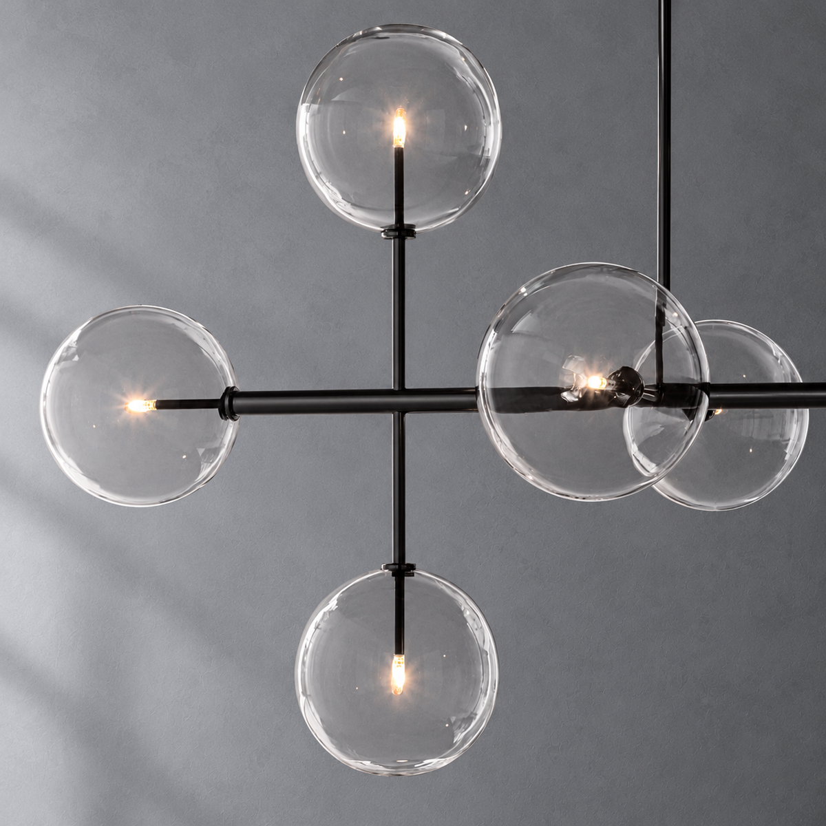 Sierra 72-inch matte black linear chandelier glass globe and metalwork detail on a textured gray background