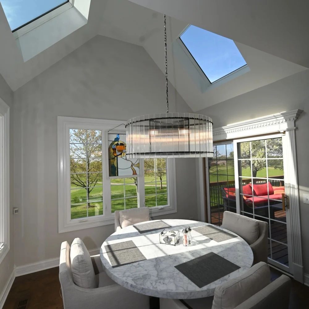 Customer installation of a crystal chandelier in a bright skylit dining room